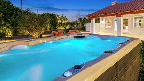 Een hottub met zwembad, omringd door tuinmeubilair en een huis met pannendak.