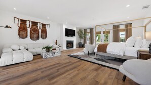 Een moderne woonkamer met een bank, fauteuils, een salontafel en een open haard.