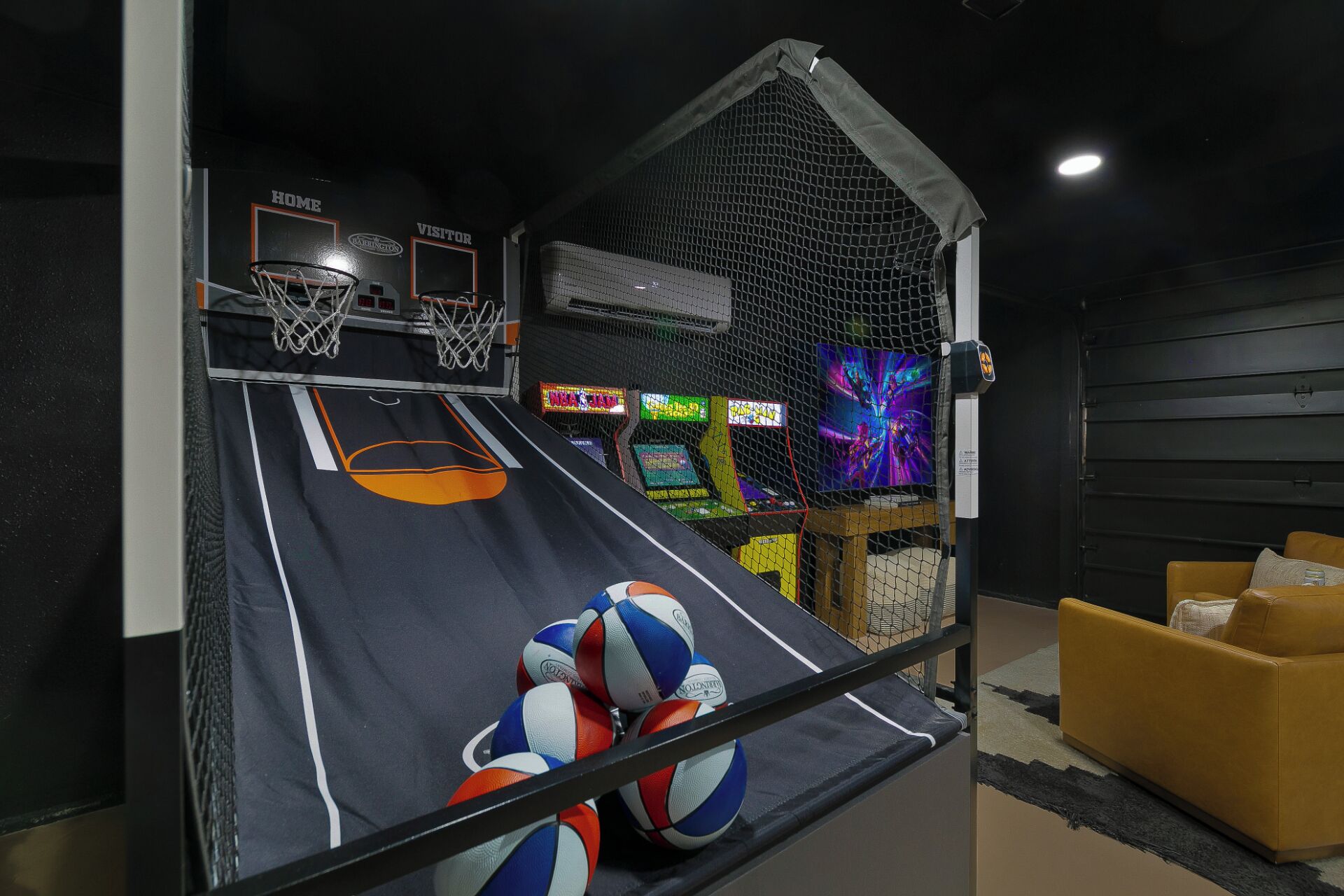 Un terrain de basket avec deux paniers, une zone de jeu délimitée par un filet et des jeux d’arcade.