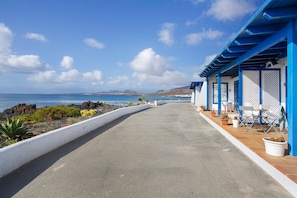 Une promenade en bord de mer offrant une vue sur la mer, un bâtiment à la façade bleue et blanche, et des sièges en plein air.