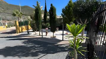 Un espace extérieur aménagé avec un revêtement pavé, agrémenté d’un pot de fleurs, d’une clôture en métal et d’arbres.