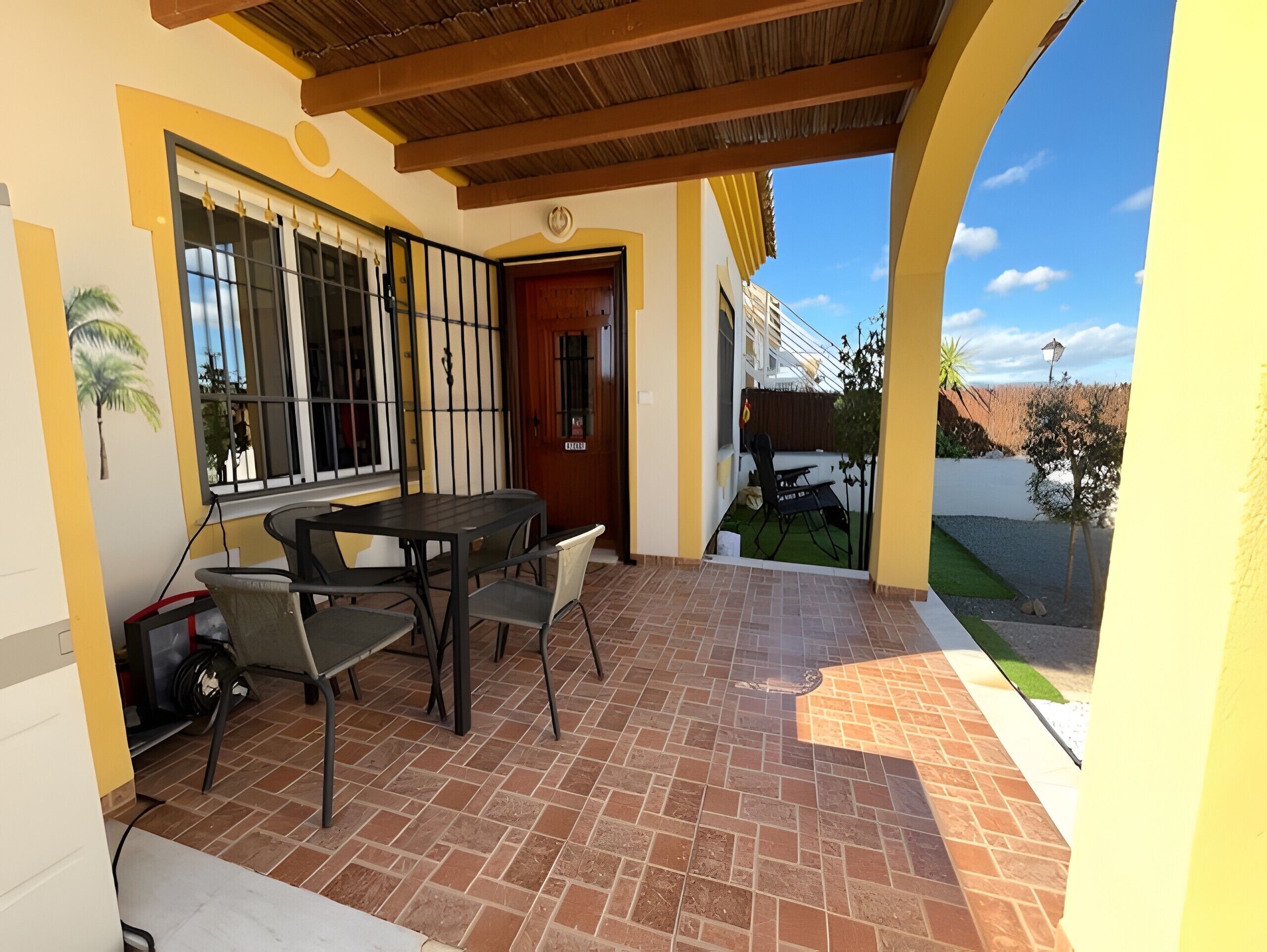 A patio with a table and chairs, a door, and a view of a residential area.