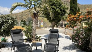 Zwei schwarze Lounge-Stühle mit Metallgestellen und Netzbespannung, ein kleiner runder Tisch und ein Kiesgrund.