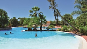 Ein Pool, umgeben von Palmen, mit einem Gebäude im Hintergrund.