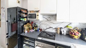 A kitchen with white cabinets, a black countertop, a microwave, a stove, and a hanging light fixture.