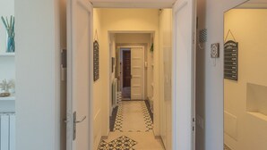 A narrow hallway with a patterned floor, white walls, and a door leading to a room. - Casa Mabel - Lecce Selection (Lecce)