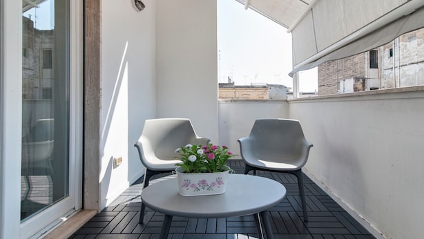 A balcony with two chairs, a small table, and a potted plant.