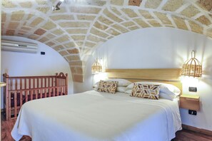 Een slaapkamer met een stenen plafond, een houten bed en twee bedlampjes.