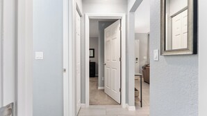 En hall med en dörr som leder in till ett rum, en ljusströmbrytare och en inramad tavla på väggen.
