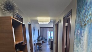 Ein Hotel-Flur mit einer Holzeinrichtung, einem Essbereich mit Stühlen und einem großen, abstrakten Gemälde an der Wand.