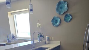 Eine moderne Küche mit einer großen Kochinsel, Edelstahlgeräten und blauen Dekorationsplatten an der Wand.