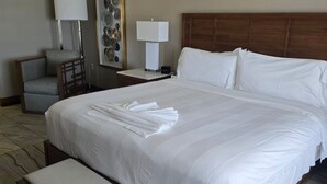 Ein Hotelzimmer mit einem großen Bett, einem Nachttisch, einem Sessel und einer Lampe.