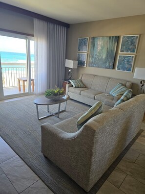 A spacious living room with a large sofa, a coffee table, and a view of the ocean through a sliding glass door. - 3 Bedroom Beachfront Condo 7 Nights Rental only Saturday to Saturday Bookings (Philipsburg)