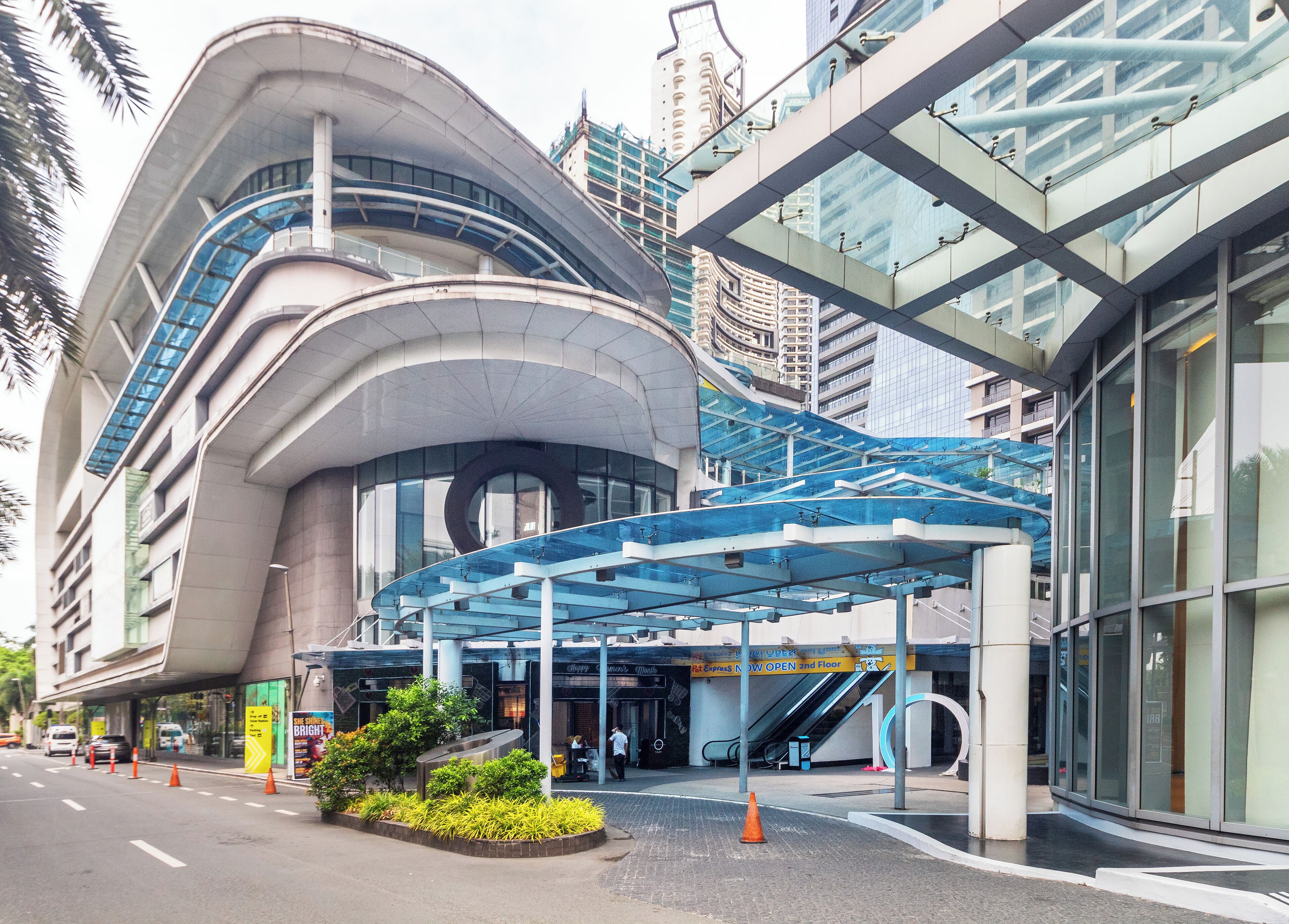 A modern building with a curved facade, a covered entrance, and an adjacent glass structure.