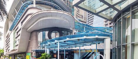 A modern building with a curved facade, a covered entrance, and an adjacent glass structure.