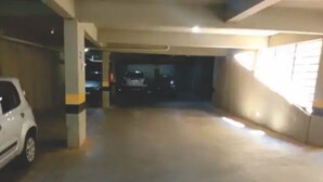 Un estacionamiento con un coche blanco aparcado a la izquierda y otro a lo lejos.