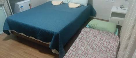 A bedroom with a large bed, a smaller bed, a desk, and a wardrobe.