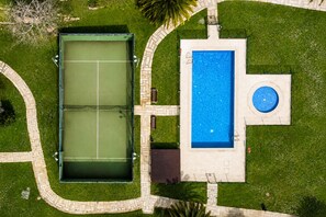A tennis court, a swimming pool, and a circular fountain.