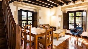 A dining area with wooden furniture, a blue chair, and large windows with views. - Tejasturias : La Franca Swimming Pool, Paddle Tennis and Beach (Noriega)