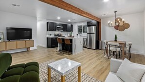 A modern kitchen with dark cabinets, a stainless steel refrigerator, and a microwave. There is a dining area with a table and chairs. - Charming 3-bedroom house in welcoming Downtown Gilbert with WiFi, AC (Gilbert)