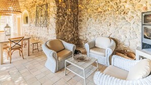 A cozy room with wicker furniture, stone walls, and a tiled floor.