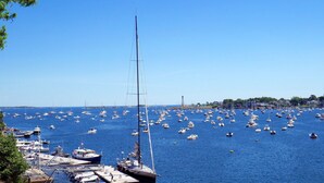 Un puerto deportivo con numerosos barcos amarrados y anclados, rodeado por un cielo azul despejado.