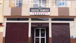 A building with a sign reading "HOSTAL KEMOVI TURISTICO" and two large garage doors.