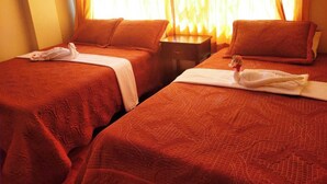 Two single beds with red bedding and white towels, a nightstand, and a window with curtains.