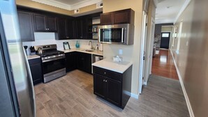 A modern kitchen with dark cabinets, stainless steel appliances, and a microwave. - Ocean Pearl-Beach block, Quick stroll to Boardwalk (Atlantic City)