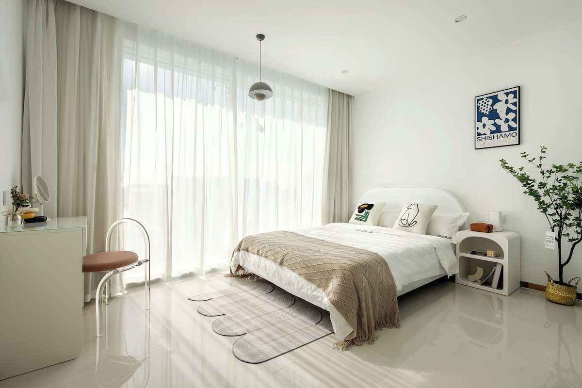 Um quarto moderno com cama, mesas de cabeceira, escrivaninha e uma cadeira.