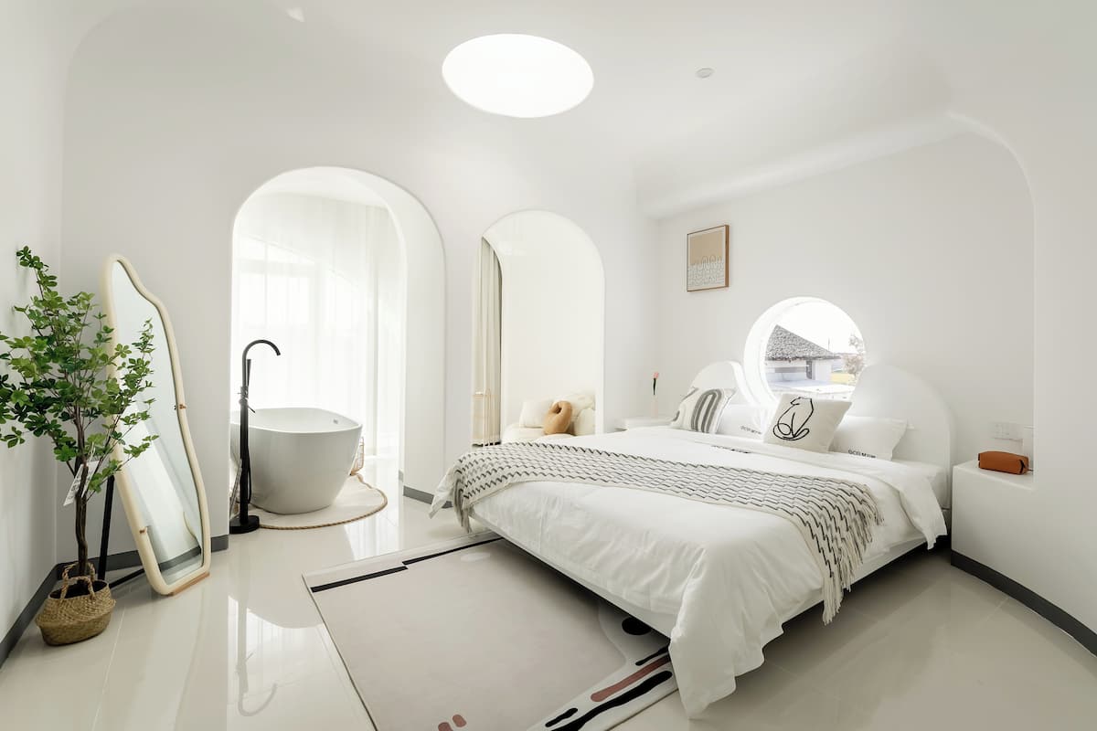 Quarto moderno com uma cama grande, uma banheira e uma planta em vaso.