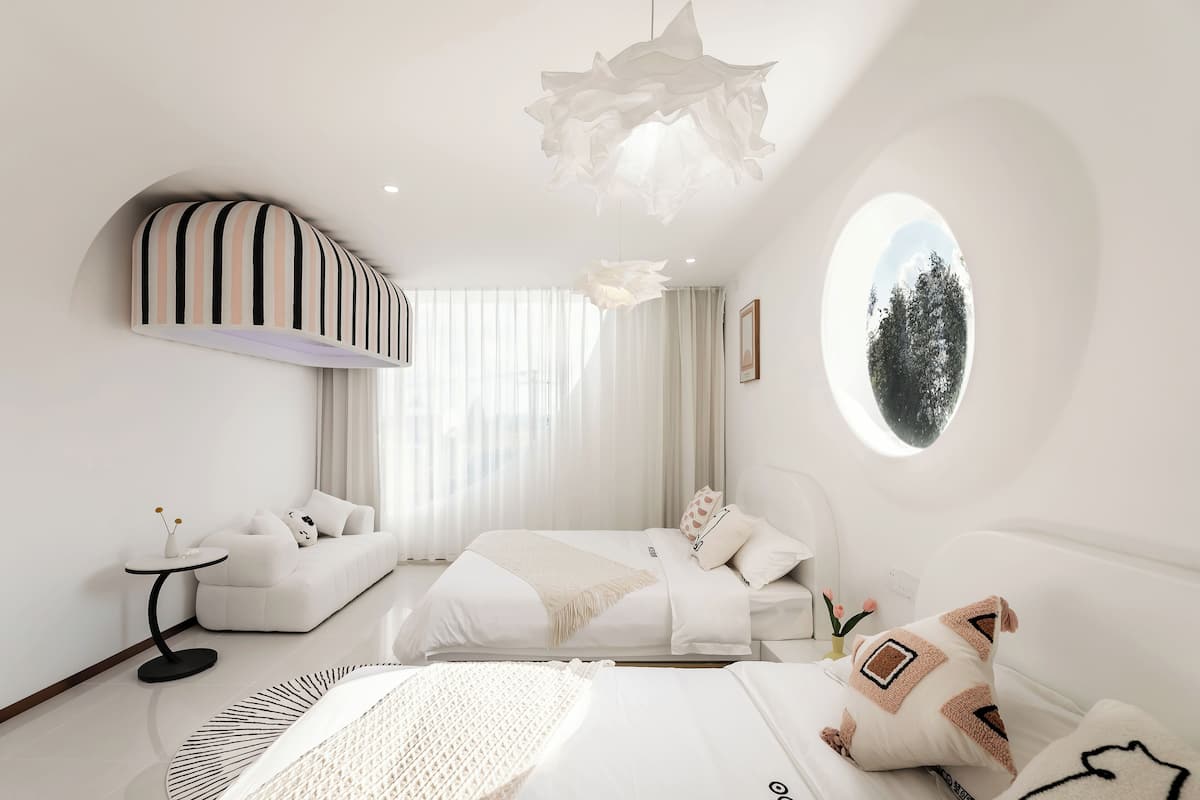 Quarto moderno com sofá, cama, mesa redonda e luminária de teto diferenciada.
