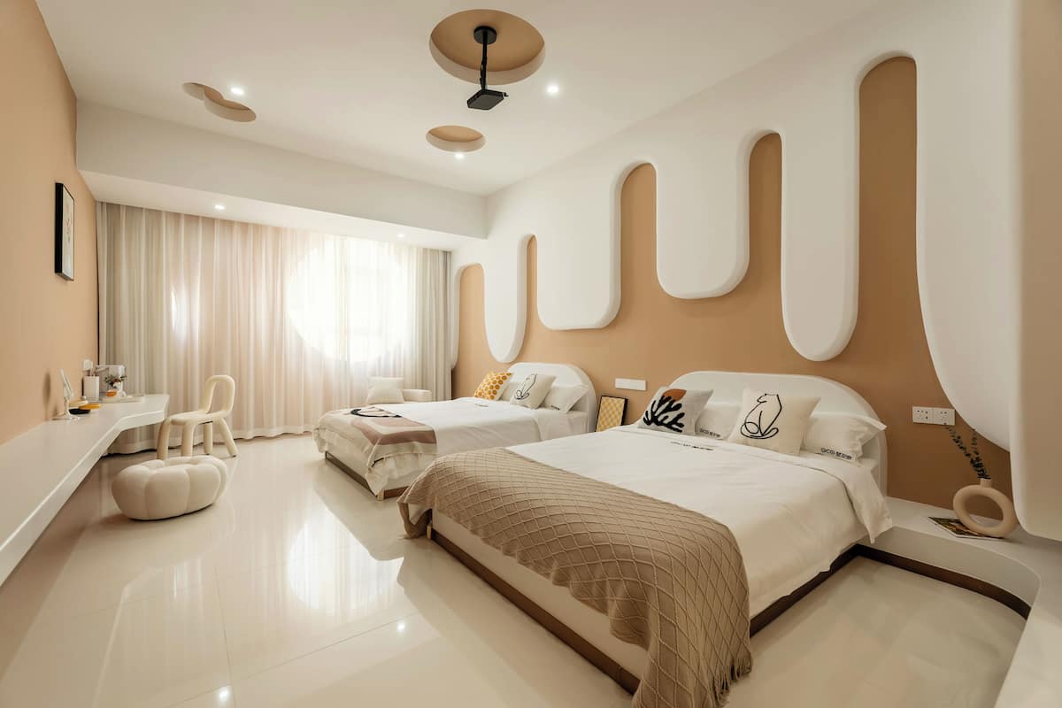 Quarto de hotel moderno com uma cama grande, uma cama menor, uma escrivaninha e um espaço de estar.