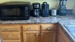 Une cuisine équipée d’armoires en bois, d’un four à micro-ondes, d’une machine à café, d’un grille-pain et d’un mixeur.