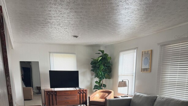 Un salon avec un canapé gris, une table basse et un téléviseur posé sur un meuble en bois.