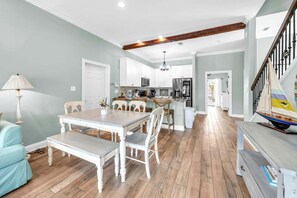 Una cucina moderna con mobili bianchi, un tavolo da pranzo in legno e una scala con una bandiera.