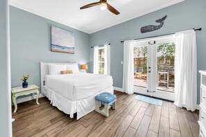 Una camera da letto con un letto, un comodino, una finestra con tende e un ventilatore a soffitto, oltre a vista sull'esterno.