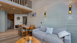A modern living room with a wooden dining table, a sofa, and a ceiling with exposed beams. - 40m from ski slopes, 2nd floor, fitness, swimming pool, sauna, balcony, fireplace or stove, tv (Les Orres)