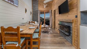 A wooden interior with a dining table set, a fireplace, and a television mounted on the wall. - 40m from ski slopes, 2nd floor, fitness, swimming pool, sauna, balcony, fireplace or stove, tv (Les Orres)