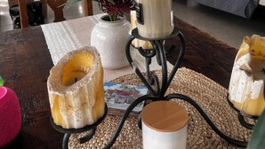 A dining table with candles, a vase with flowers, and a placemat.