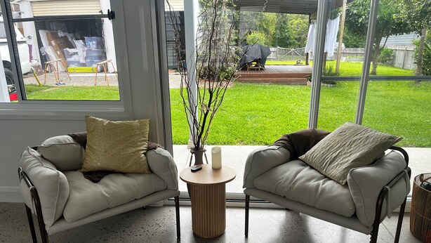 A modern living room with two sofas, a round coffee table, and a view of a backyard.