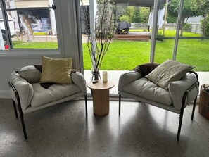 Ein modernes Wohnzimmer mit zwei Sofas, einem runden Couchtisch und Blick auf einen Garten.