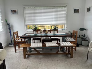 Ein Essbereich mit einem Holztisch, gepolsterten Bänken und Topfpflanzen.