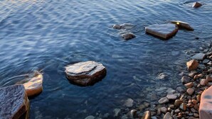 A sunset over a calm sea with rocks in the foreground. - Family Retreat | Game Room + EV Charger (Sturgeon Bay)