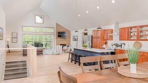 A spacious kitchen with wooden cabinets, a large island, and a dining area with a wooden table and chairs. - Family Retreat | Game Room + EV Charger (Sturgeon Bay)