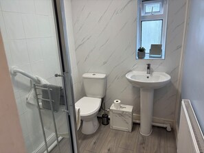 A bathroom with a glass shower enclosure, a toilet, a sink, and a mirror. - Coedmor (Newport)