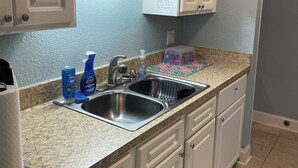 Una cocina con armarios blancos, encimera de granito, pileta doble y salpicadero decorativo.