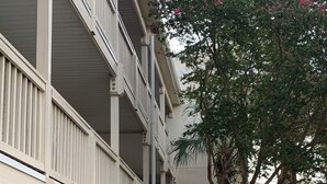 Un edificio de varios pisos con un corredor cubierto y una zona de estar al aire libre.