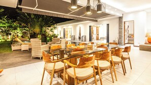 Un comedor amplio con una mesa de cristal y sillas de madera, rodeado de un jardín exuberante y decoración moderna.