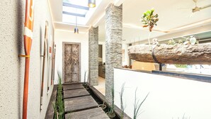Un interior moderno con un sendero de madera, pilares de piedra y una planta colgante.